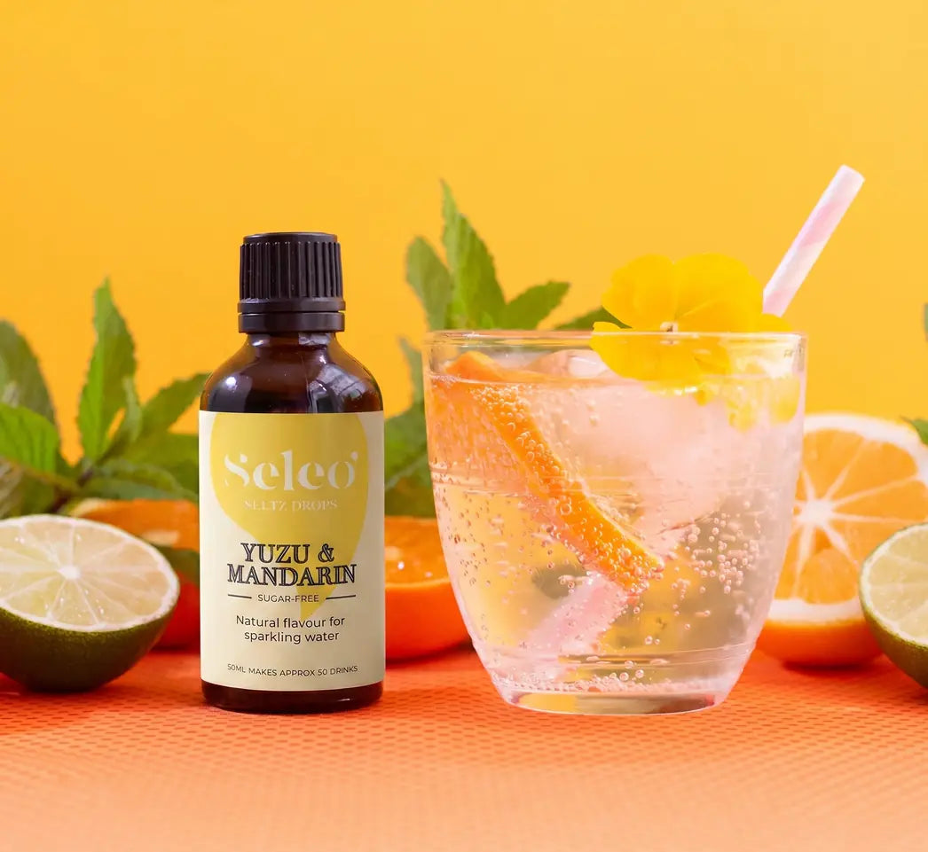 Premium Seleo Yuzu and Mandarin seltz drops presentation with citrus sparkling water in Kuwait - طريقة تقديم قطرات نكهة اليوزو والماندرين المنعشة من سيلو مع الصودا والثلج، فخامة وانتعاش مثالي لمشروبات الصيف في الكويت - 100% Sugar-free.