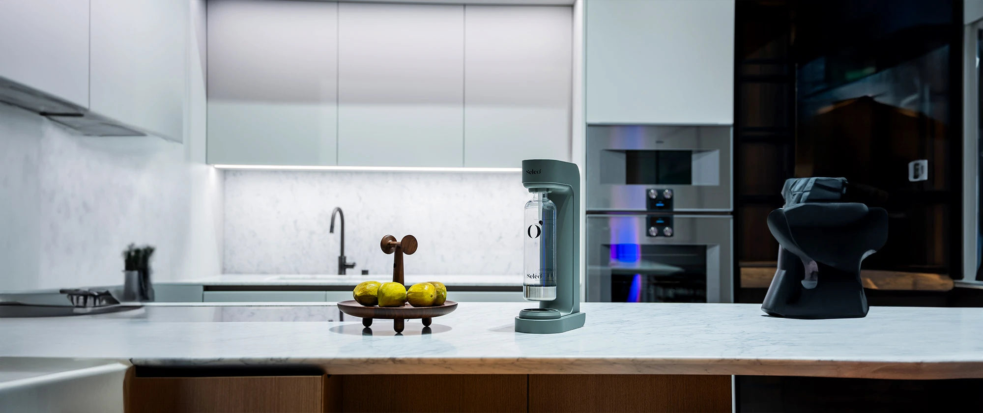 Seleo premium carbonating water maker in sage green on a marble kitchen island with fresh lemons, minimalist modern home decor.